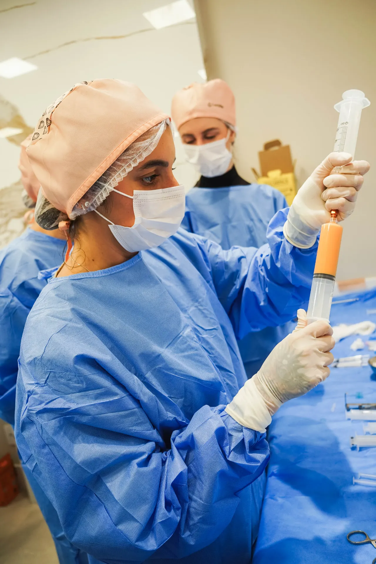 Médica em procedimento de lipoenxertia com seringa em ambiente cirúrgico